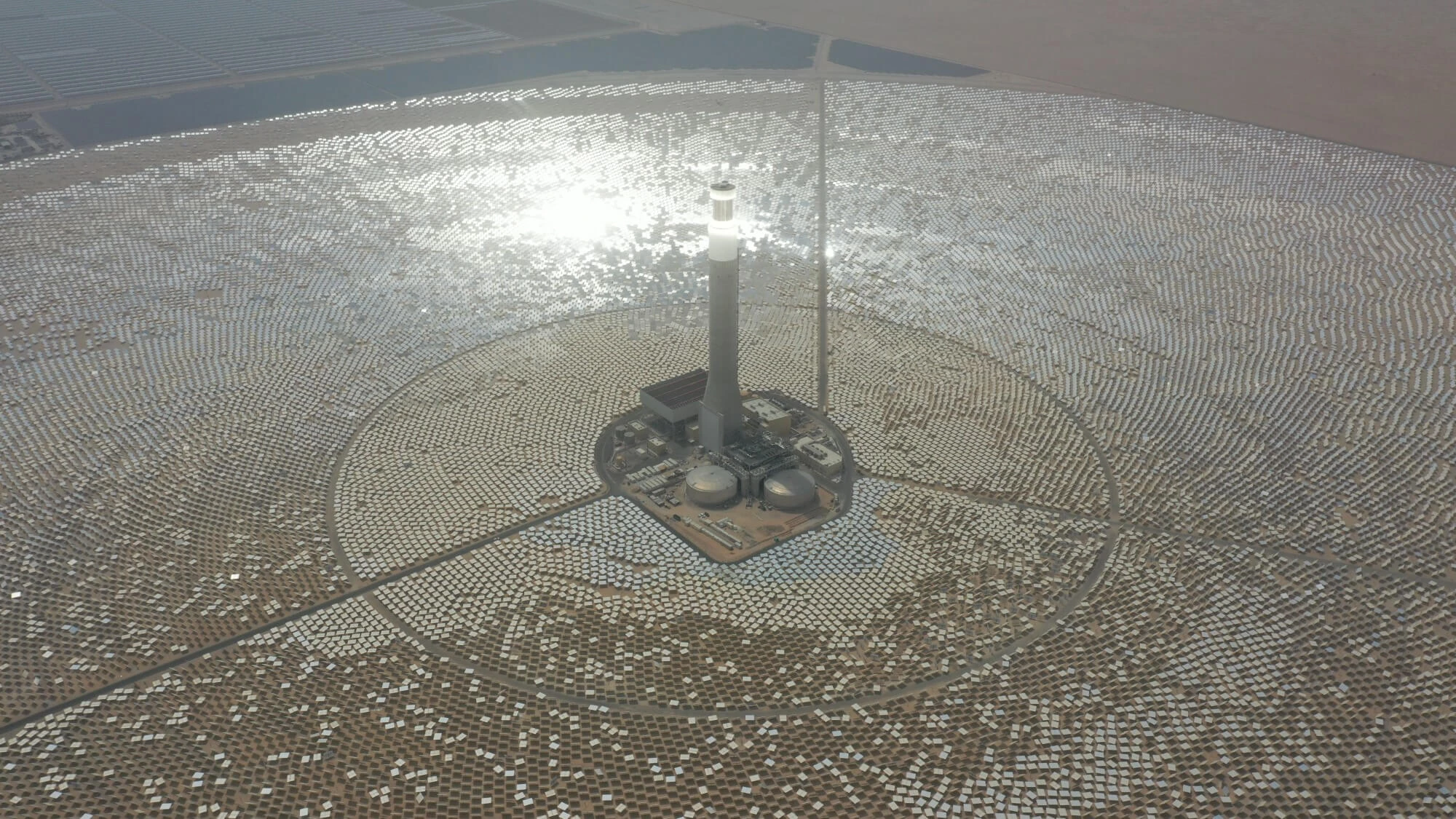 Aerial photograph of the central solar tower, thermal-storage tanks and heliostat field at Noor Energy 1 in Dubai